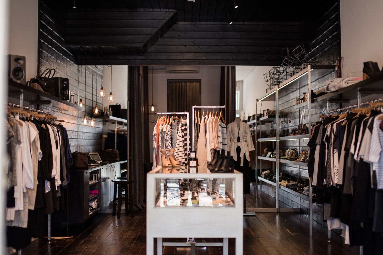 Boutique de vêtements aux murs sombres, éclairée par des suspensions